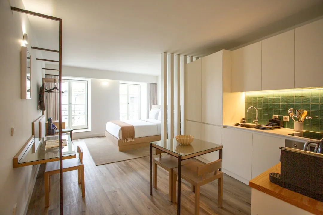 Studio apartment with layered dividers separating sleeping zone from kitchen and dining area with wood floors