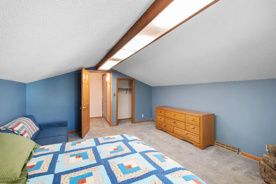 Attic bedroom with sloped ceiling, blue walls, wood dresser, and quilt-covered bed showcasing smart layout design
