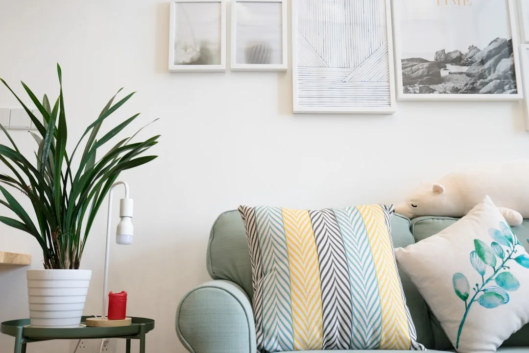 Green sofa with colorful herringbone throw pillow, botanical cushion, and stuffed bear in a Scandinavian-style living ro