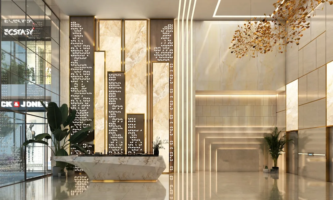 Luxury hotel lobby entrance with marble reception desk, gold decorative chandelier, and ornate patterned wall panels