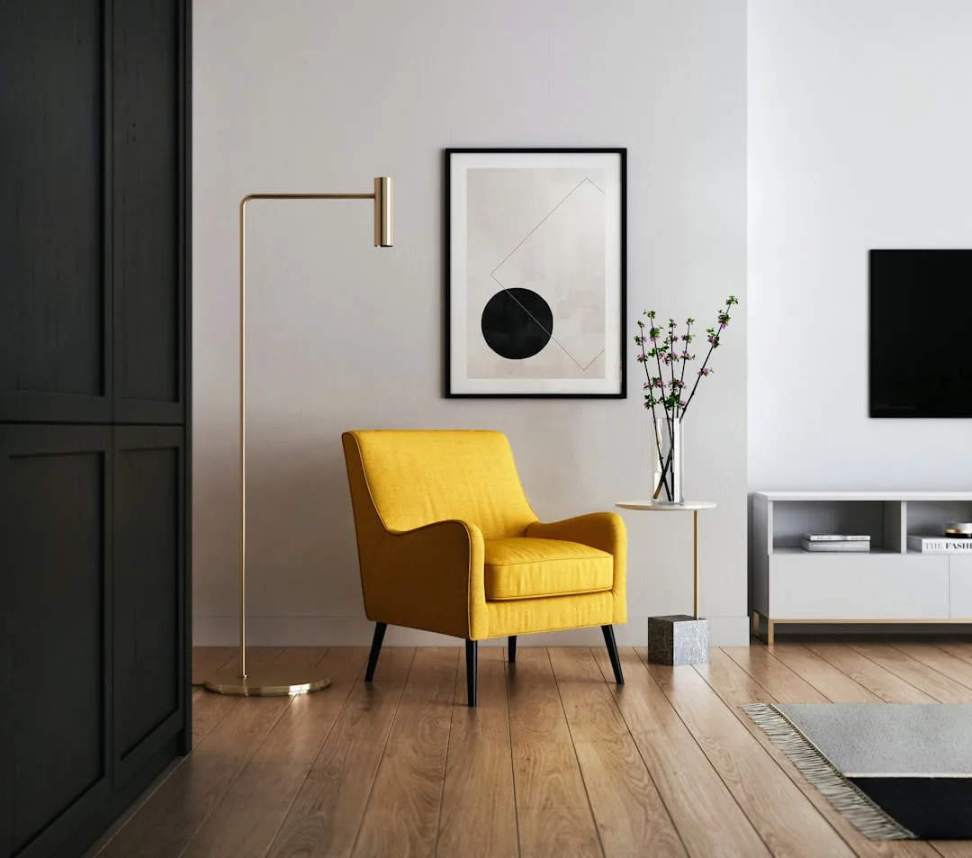 Modern living room with mustard yellow accent chair, gold floor lamp, abstract wall art, and minimalist white media cons