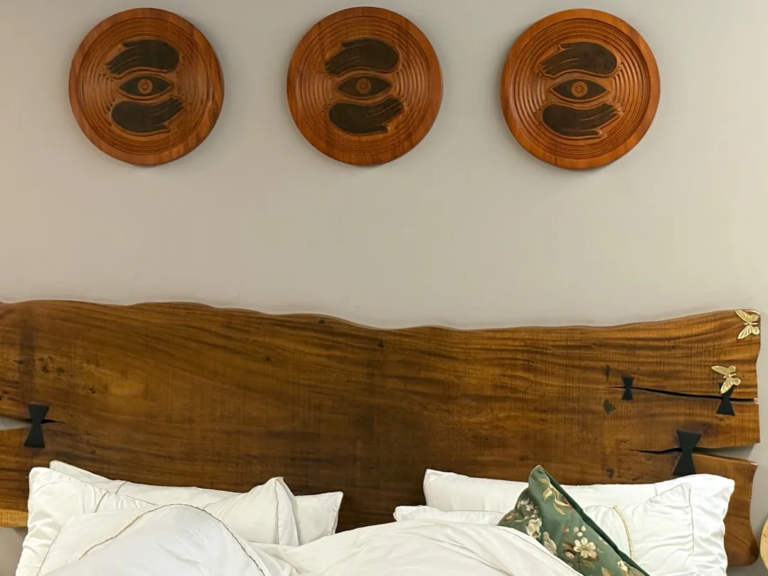 Three round wooden wall art pieces hung above a live-edge wood headboard bed with white pillows