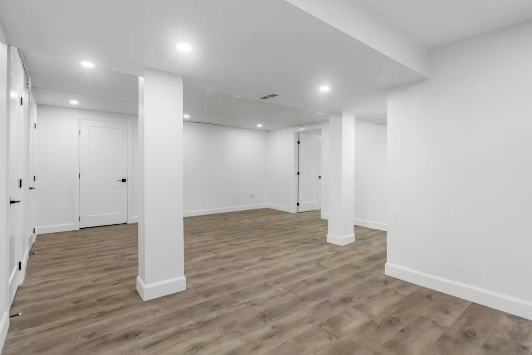 Finished basement with white walls, luxury vinyl plank flooring, recessed lighting, and two white interior doors