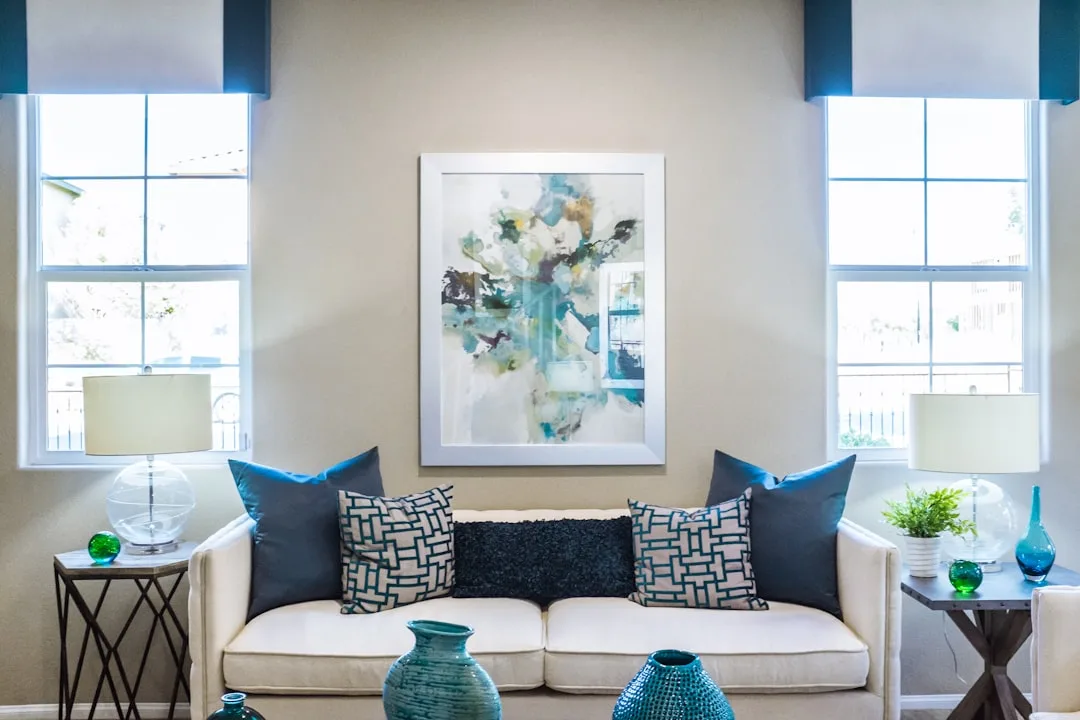 Living room with white double-hung windows featuring blue valances above a white sofa with decorative pillows