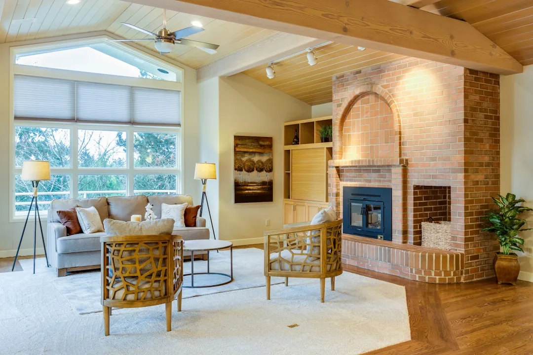 Warm living room with beige walls, brick fireplace, and natural light showing how paint colors appear in real interior s