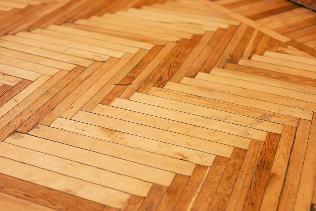 Close-up of herringbone parquet wood flooring pattern showing alternating light and dark wood plank arrangement