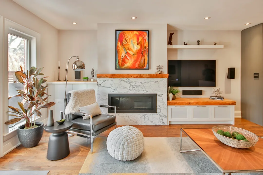Modern living room with recessed lighting illuminating framed abstract artwork above a marble fireplace
