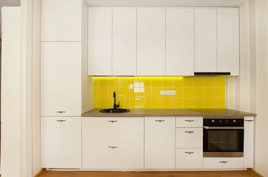 Modern white kitchen with bright yellow tile backsplash, white cabinets, and built-in oven showing color impact on small