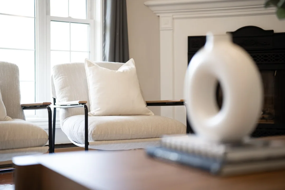 Modern white accent chair with cushion beside fireplace in minimalist living room affordable decorating
