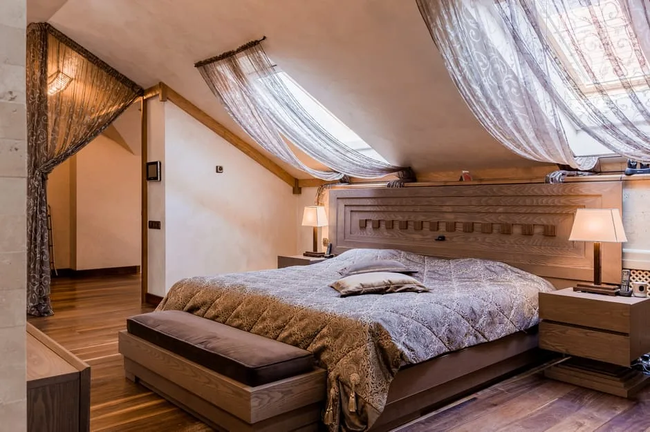 Luxury attic bedroom with slanted ceiling, skylight windows, wooden platform bed and sheer curtains