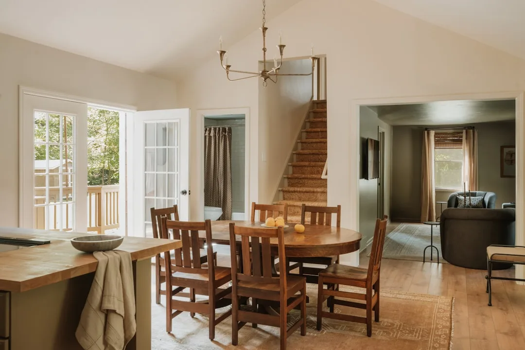 Farmhouse dining room with round wood table, Mission-style chairs, chandelier, and French doors in 2025 interior style