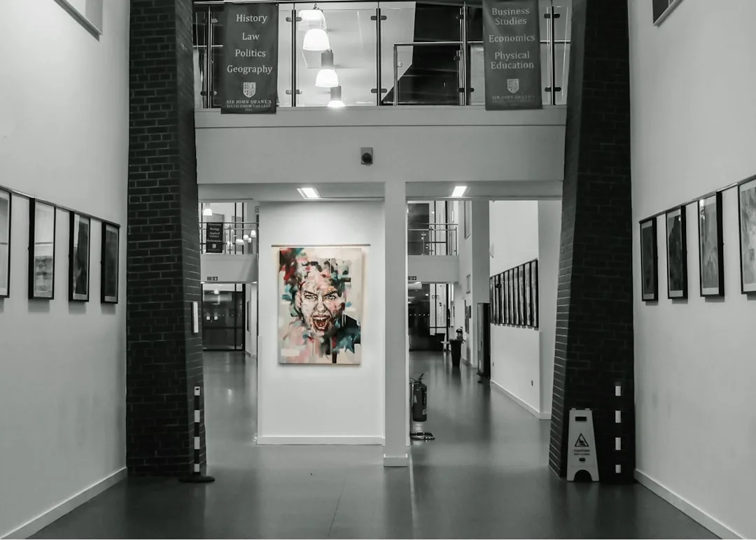 Gallery wall with framed artwork lining both sides of a modern hallway corridor in an educational building