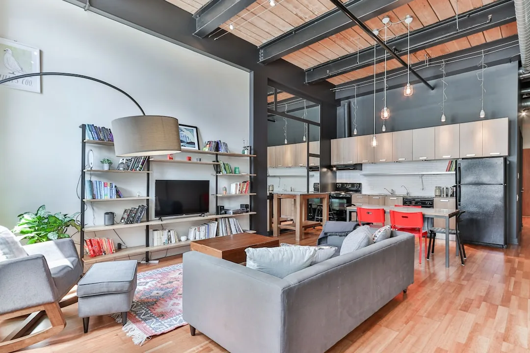 Industrial loft interior with exposed steel beams, wood ceiling, open-plan living and kitchen area in 2025 design style