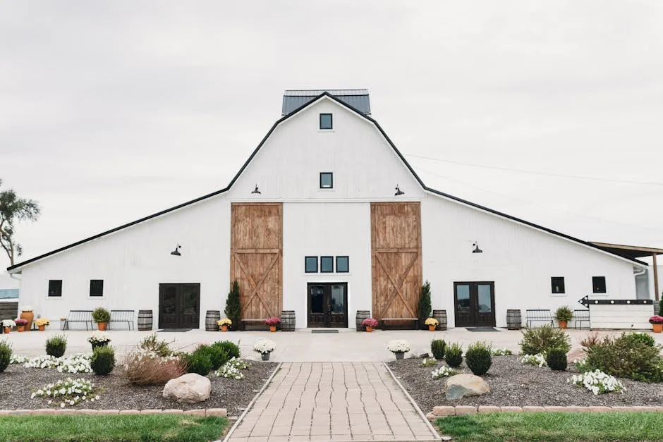 Modern farmhouse design center exterior with white barn structure, wooden sliding doors, and landscaped pathway
