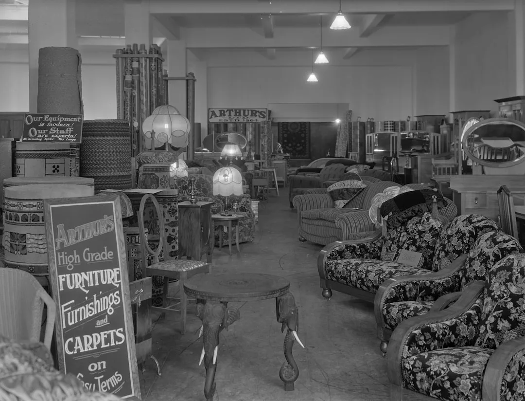Vintage black and white photo of Arthur's furniture showroom displaying sofas, armchairs, lamps, and carpets circa 1920s