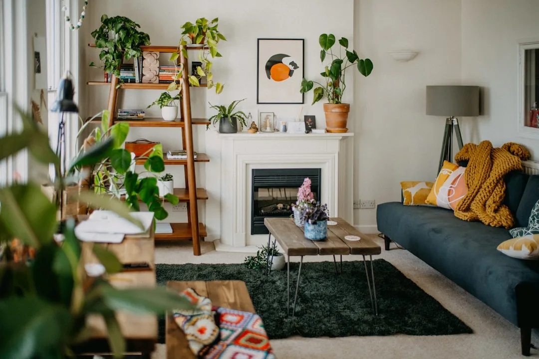 Budget living room makeover with ladder shelf, navy sofa, fireplace, houseplants, and layered rugs