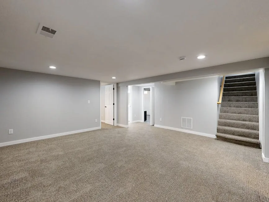 Finished basement with beige carpet, gray walls, recessed lighting, staircase, and open doors showing utility room