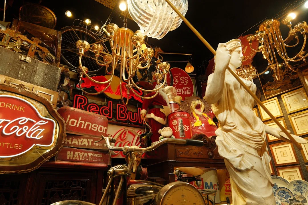 Vintage antique shop display with classical statue, brass chandeliers, Coca-Cola signs, and eclectic collectibles