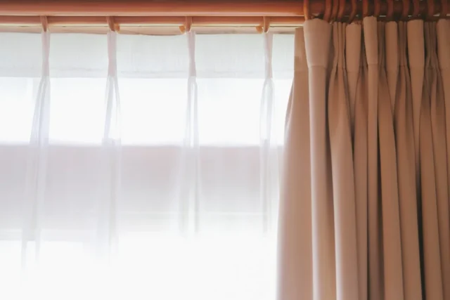 Sheer white curtains and beige pinch-pleat drapes