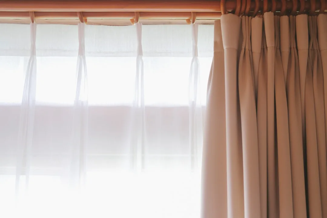 Sheer white curtains and beige pinch-pleat drapes