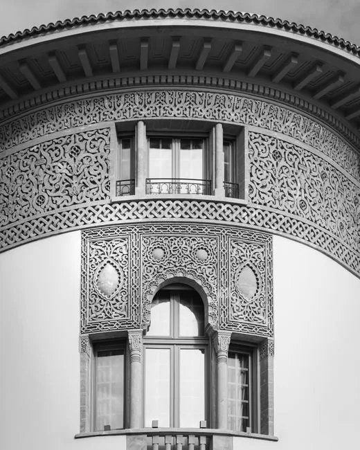 Louis Sullivan-style ornamental architectural facade with intricate Moorish relief carvings and arched windows in black 