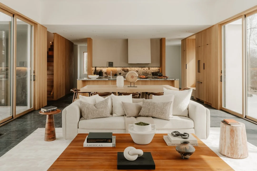 Minimalist open-plan living room with cream sofa and warm wood kitchen in neutral tones