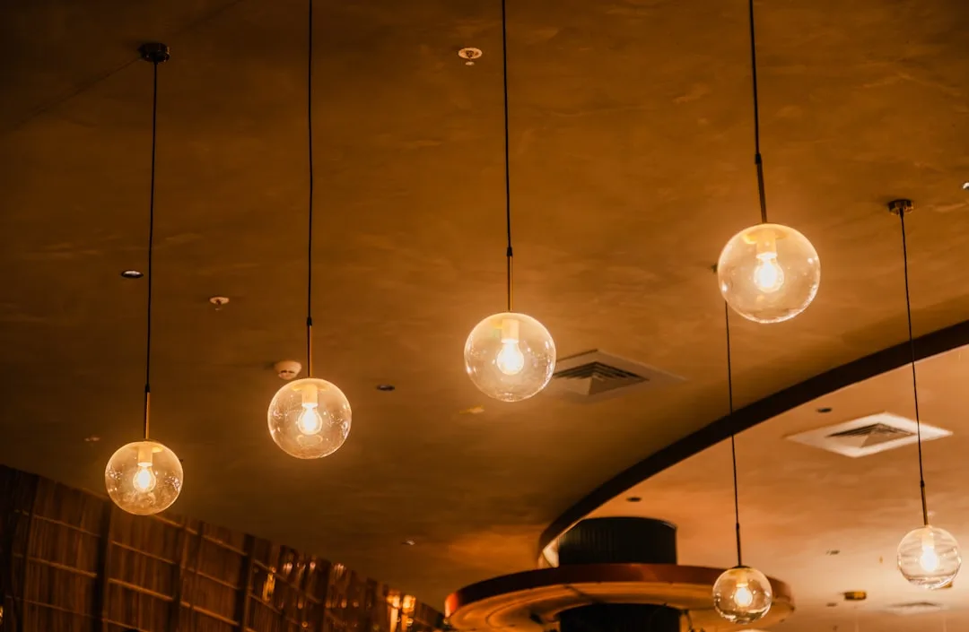 Globe pendant lights with Edison bulbs hanging from warm-toned ceiling in modern restaurant interior