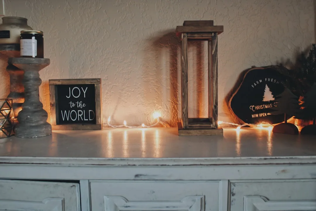 Farmhouse Christmas mantel with string lights, Joy to the World sign, wooden lantern and rustic decor