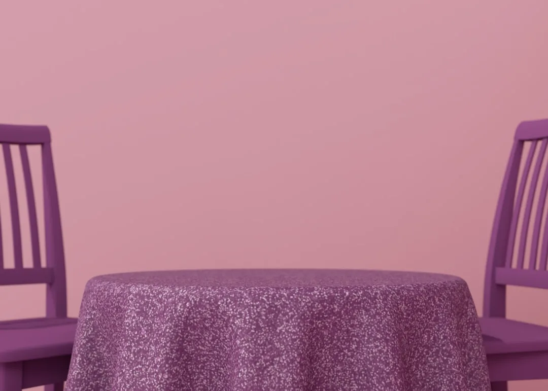 Purple chairs and round table with patterned tablecloth against a pink wall in a monochromatic styled room