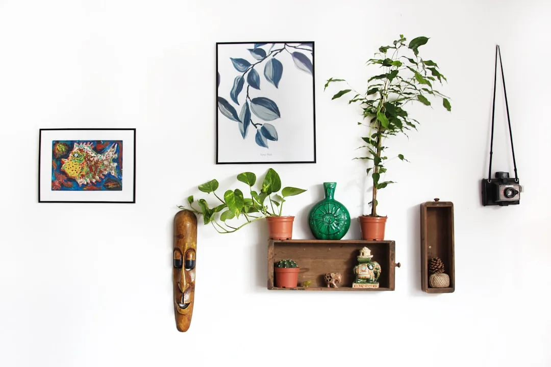 Eclectic gallery wall with botanical print, colorful fish art, potted plants, wooden shelf, tribal mask, and vintage cam