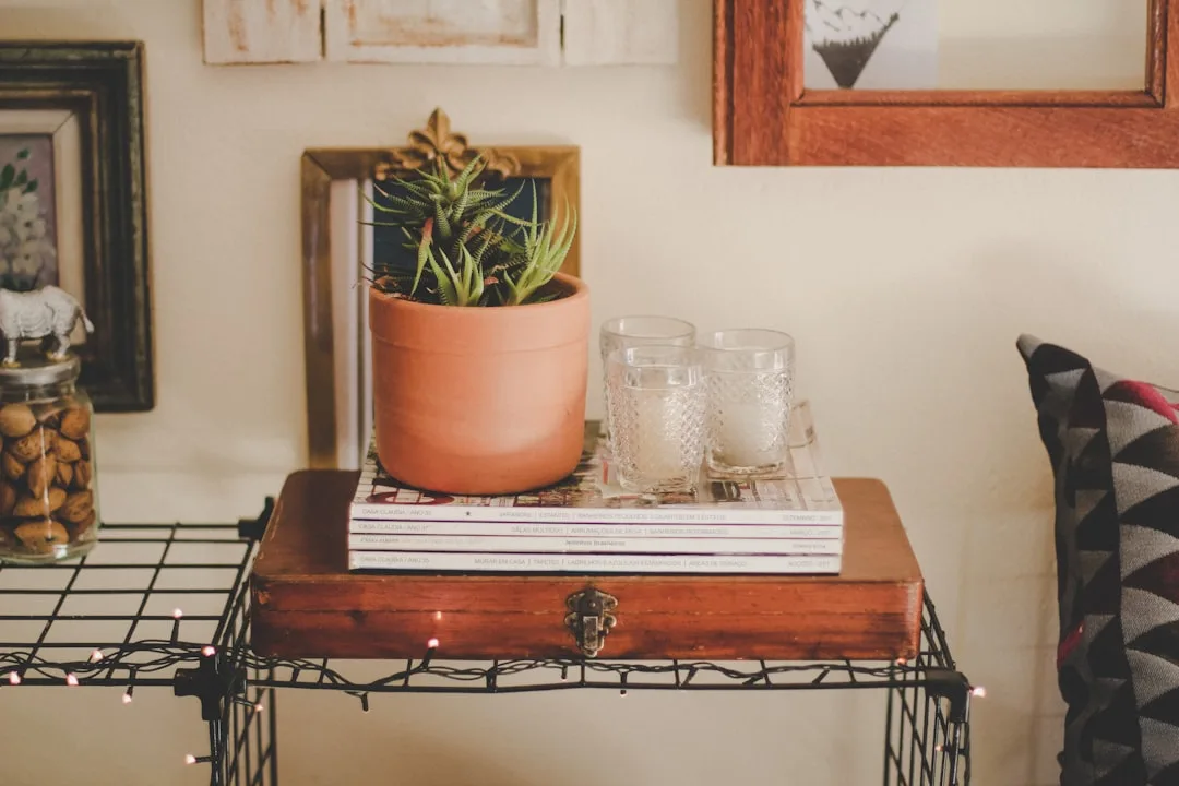 Styled side table with stacked magazines, terracotta succulent pot, glass candles, and fairy lights for a curated shelf