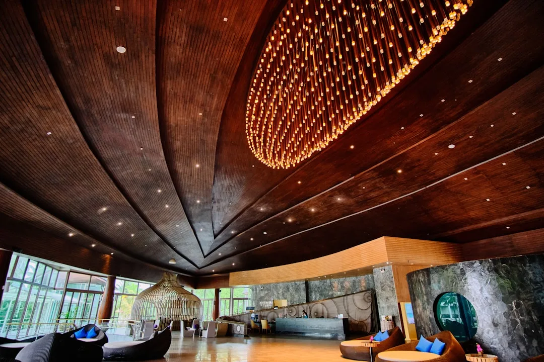 Luxury hotel lobby with dramatic wooden curved ceiling and massive pendant chandelier used as architectural lighting des