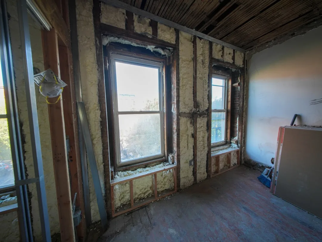 Interior wall cavity with spray foam insulation visible between wood studs during home renovation construction