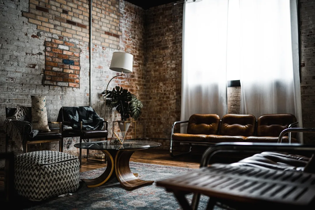 Industrial loft living room with exposed brick walls, brown leather sofa, vintage coffee table and floor lamp