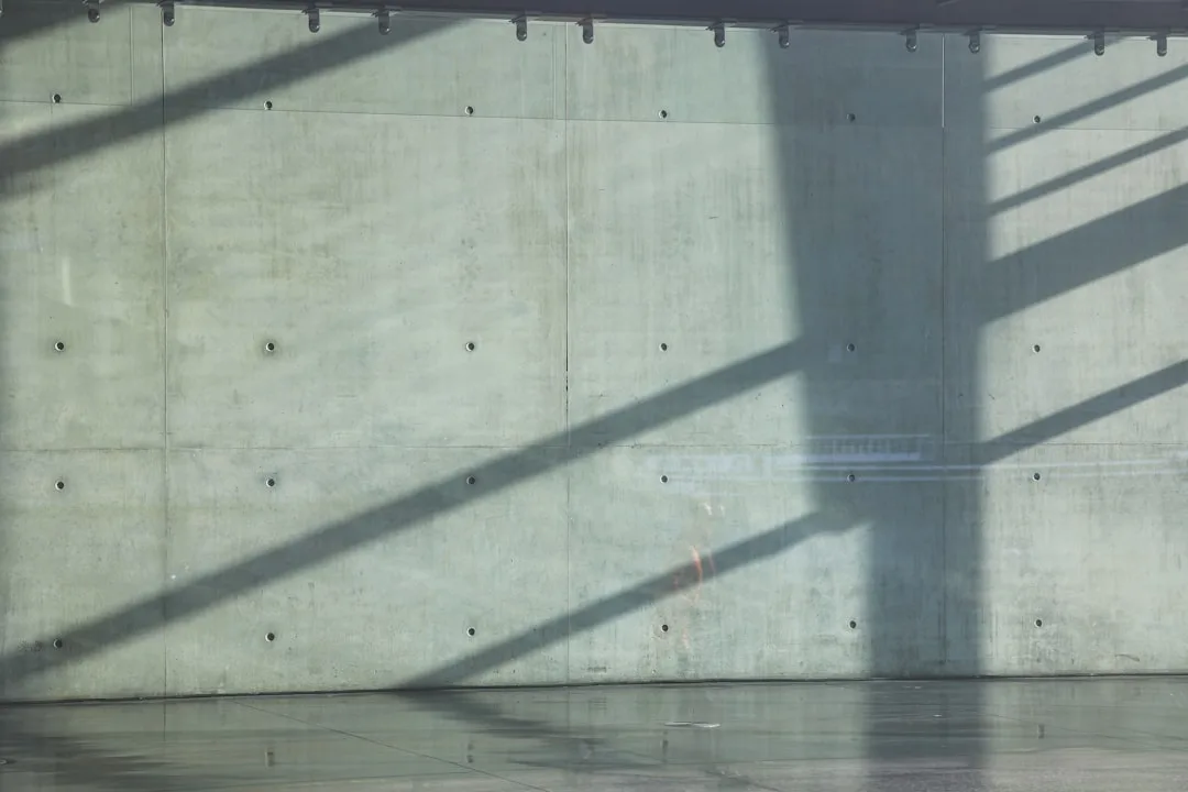 Exposed concrete walls with dramatic shadow patterns in a raw structural interior space