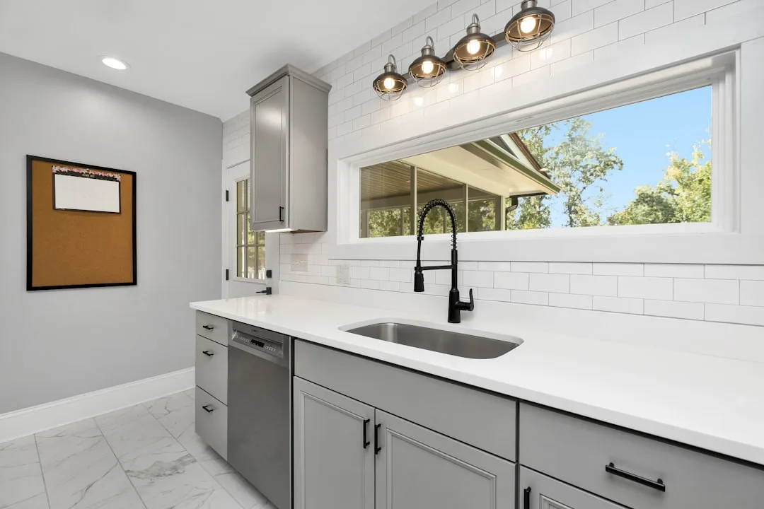 Newly remodeled kitchen with gray shaker cabinets, white quartz countertops, subway tile backsplash, and stainless steel