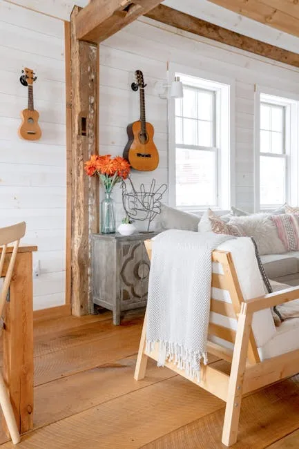 Modern farmhouse living room with wood beam ceiling, guitars on wall, linen chair, and layered neutral textiles