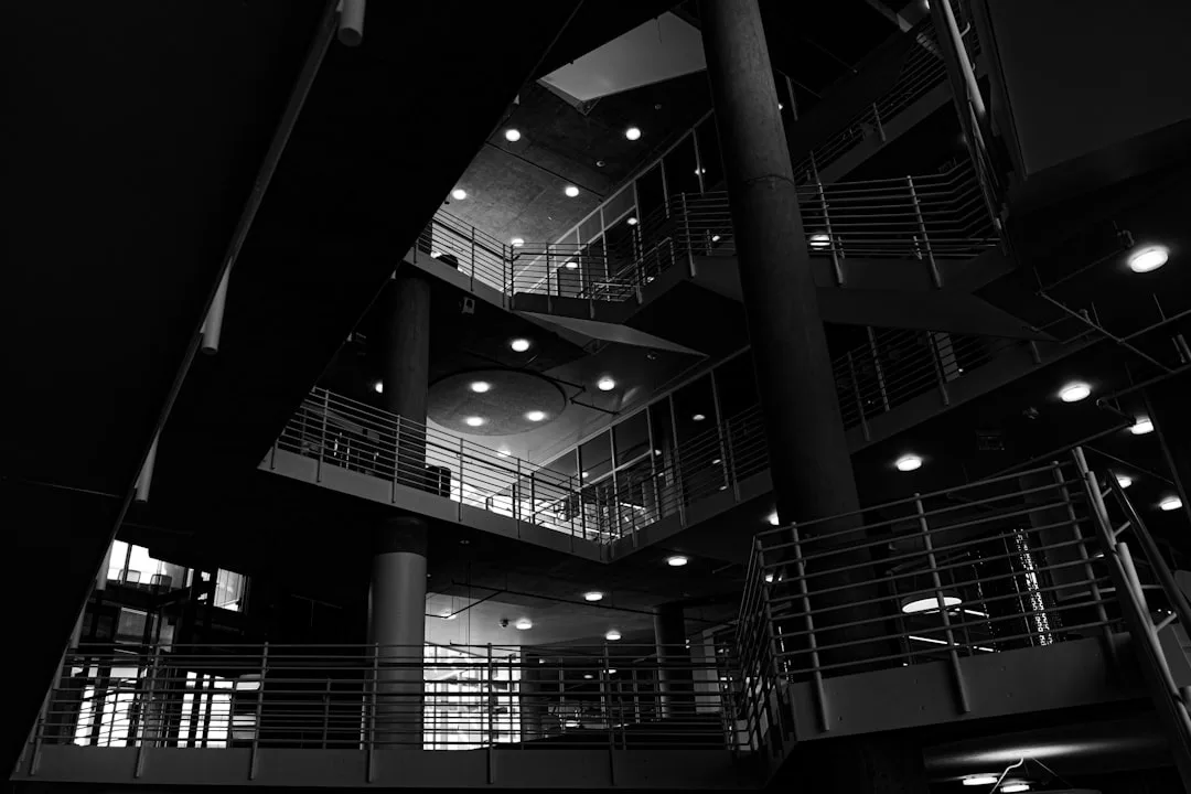 Multi-level building interior with layered ceiling lights and metal railings in dramatic black and white architecture ph