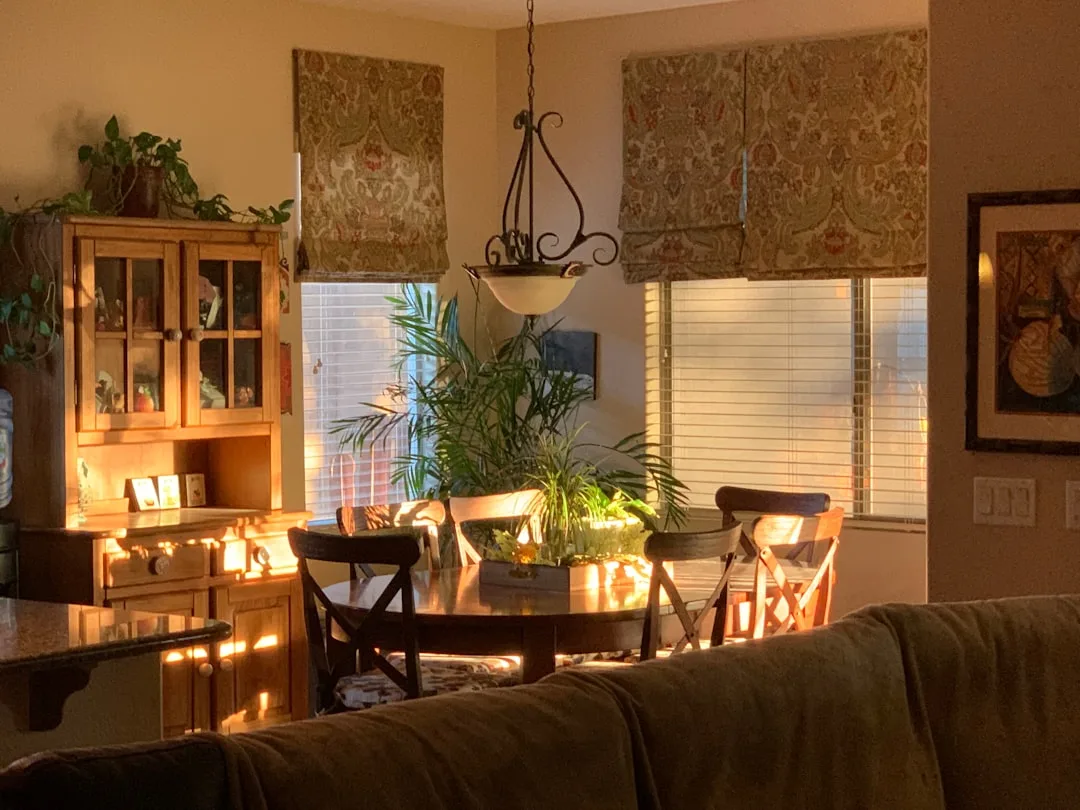 Warm dining room with pendant light and natural window light creating layered ambient lighting effect