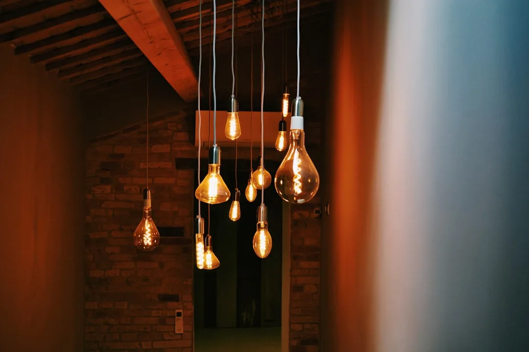 Multiple vintage Edison pendant bulbs hanging in a hallway with exposed brick walls and warm ambient lighting