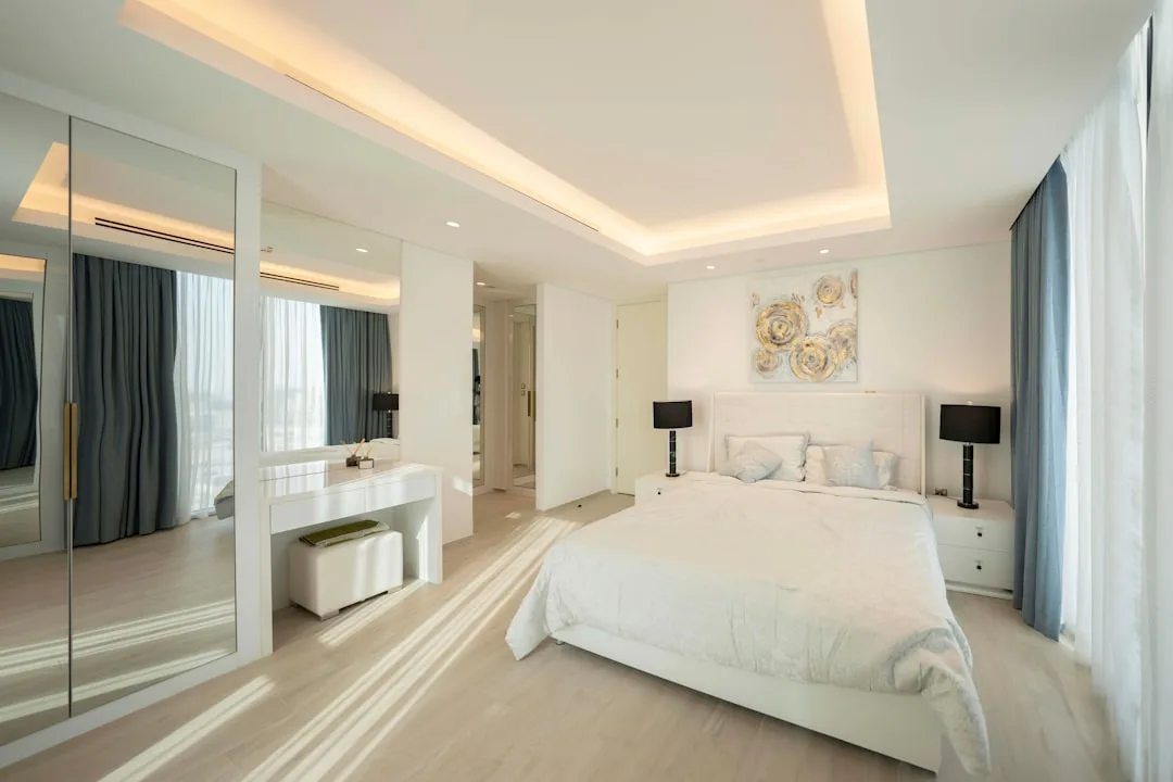 Spacious modern bedroom with corner vanity desk area, mirrored wardrobe, and open floor plan layout