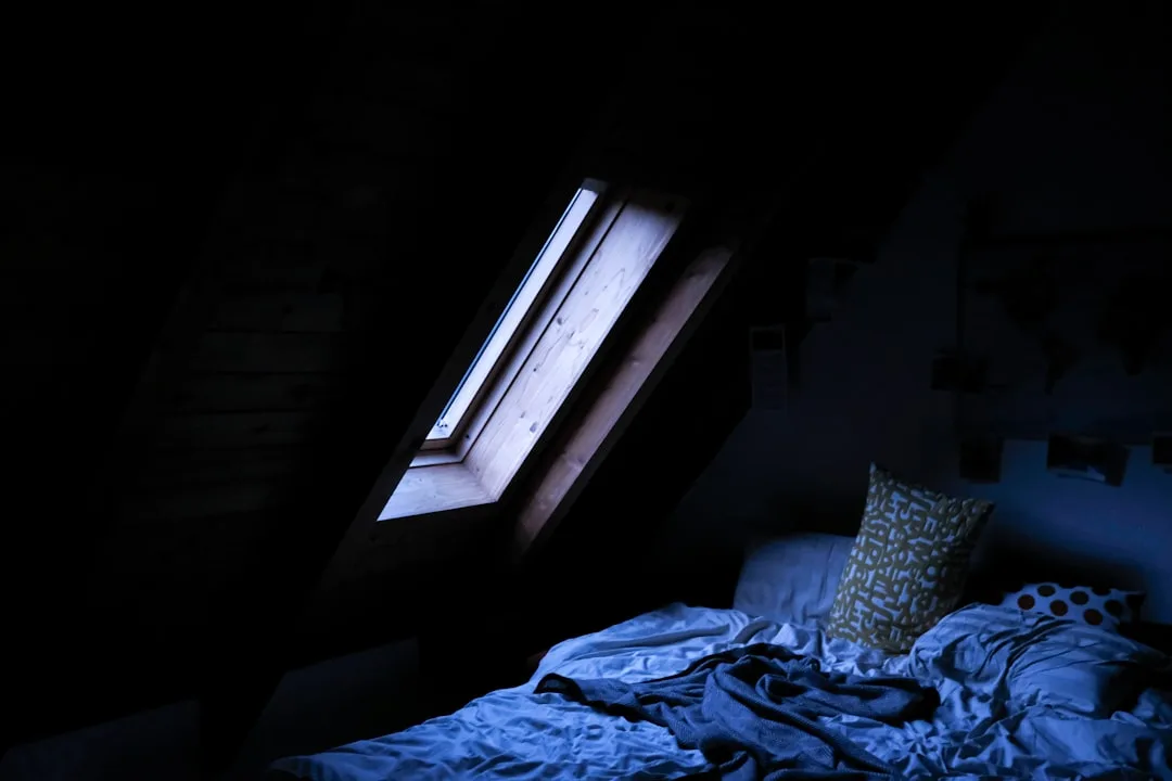 Dark attic bedroom with skylight window showing temperature and ventilation challenges in loft conversion spaces