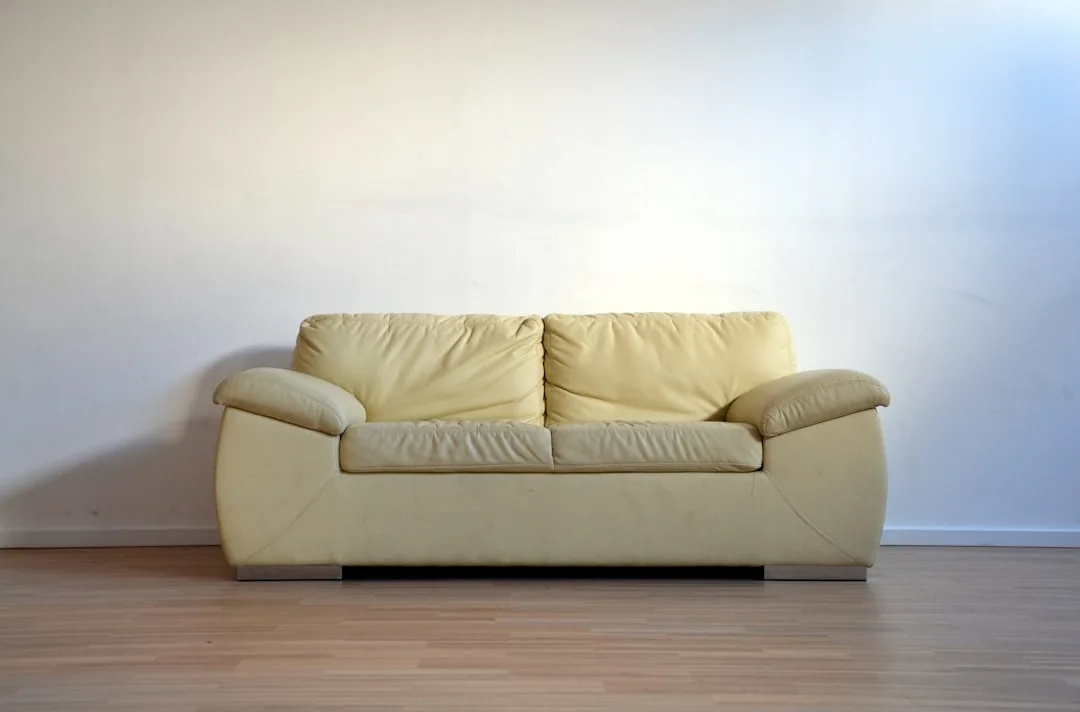 Yellow leather sofa placed flat against a white wall on hardwood floor illustrating common furniture placement mistake