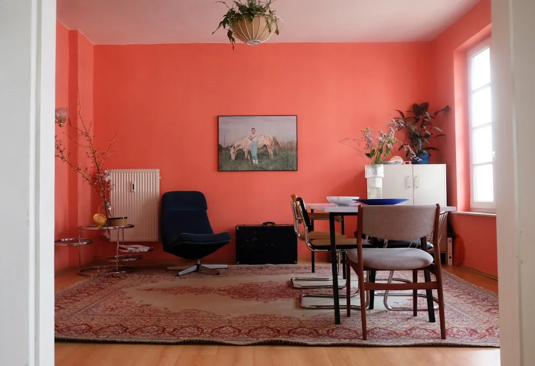 Bold coral-red painted living and dining room with mismatched furniture showing impact of strong paint color choice