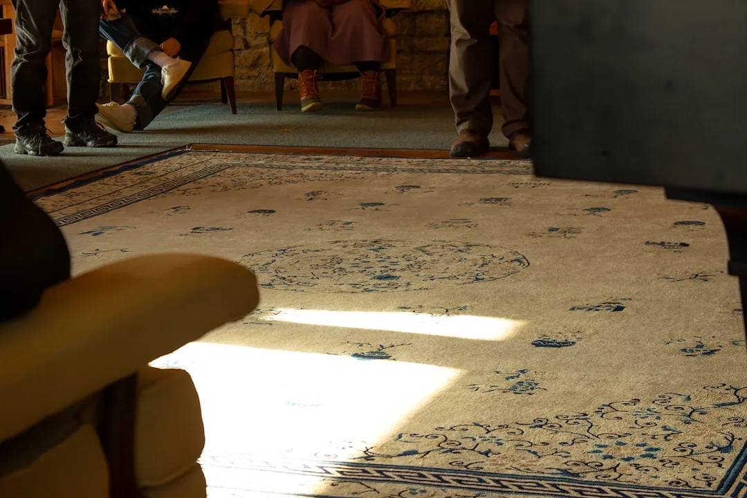 Ornate blue and cream area rug in living room showing proper sizing with furniture legs anchored on rug
