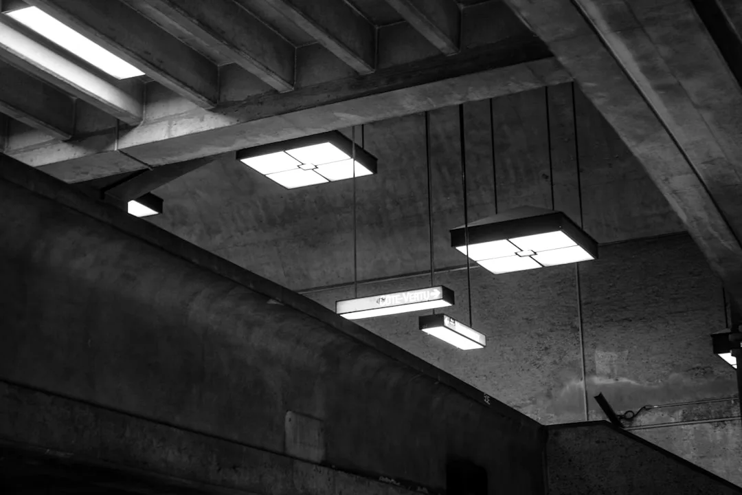Industrial ceiling with square overhead pendant lights in a concrete parking structure, black and white photography