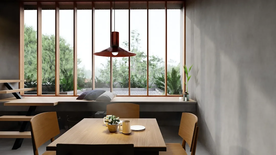 Japandi dining nook with wooden table, pendant lamp, window bench and lush garden view showing intentional layout philos