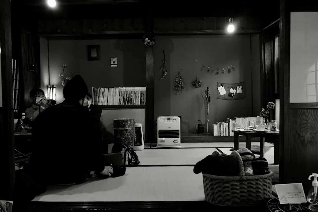 Traditional Japanese room with warm dim lighting, kerosene heater, tatami floor, and wood bookshelves in Japandi style