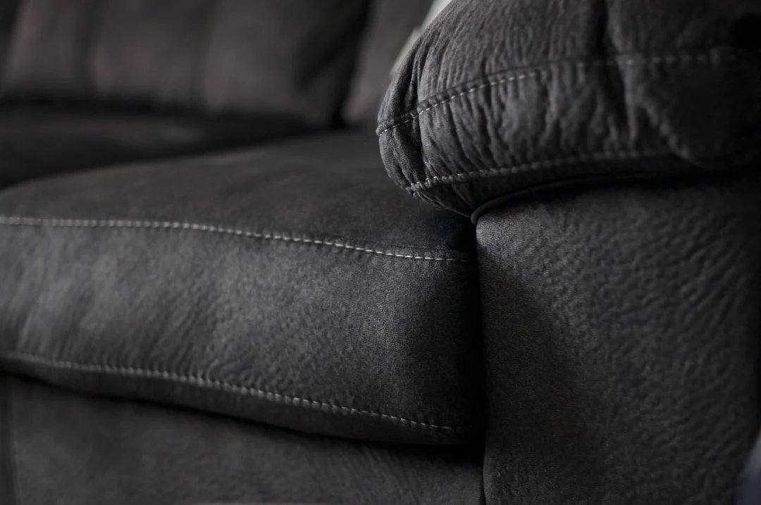 Oversized deep-seated dark upholstered sofa with plush cushions and detailed stitching