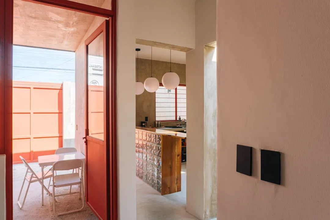 Modern small interior space with globe pendant lights, glass block kitchen island, and open doorway to sunlit coral pati